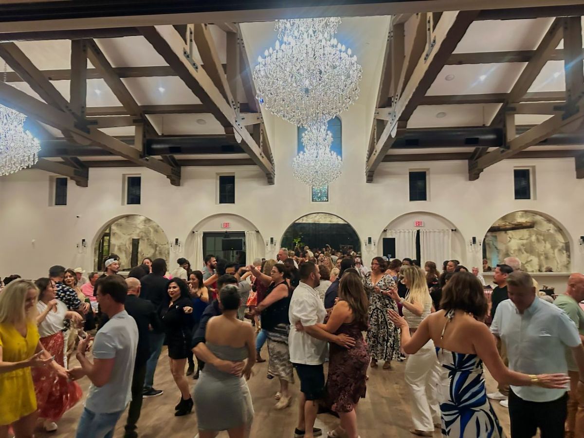 A full dance floor under crystal chandeliers at an elegant reception